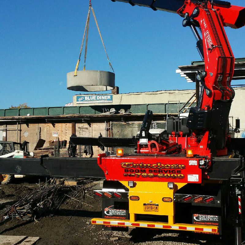 Truck-mounted crane with boom extended over a building